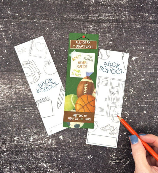 Three back-to-school-themed bookmark cards are arranged on a dark wood surface. One card is blank and white with school icons, one is partially filled in with a green header and sports illustrations, and one is mostly blank.