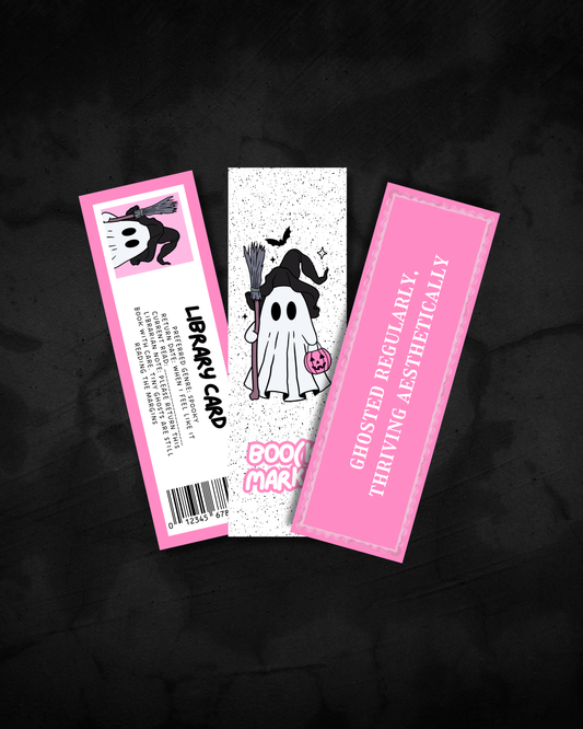 Three Halloween-themed library cards displayed on a dark textured background. The left card is pink with a cartoon witch and the text 'LIBRARY CARD'.