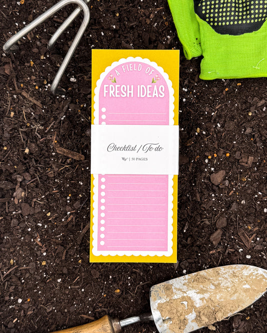 Notebook with 'Fresh Ideas' cover on a soil background with gardening tools