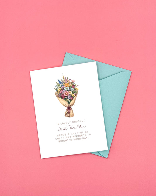 Greeting card with a floral bouquet, a blue envelope and a pink background