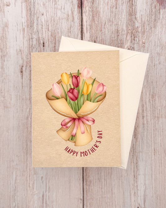 Greeting card with a illustration of tulips and 'Happy Mother's Day' text on a wooden surface.