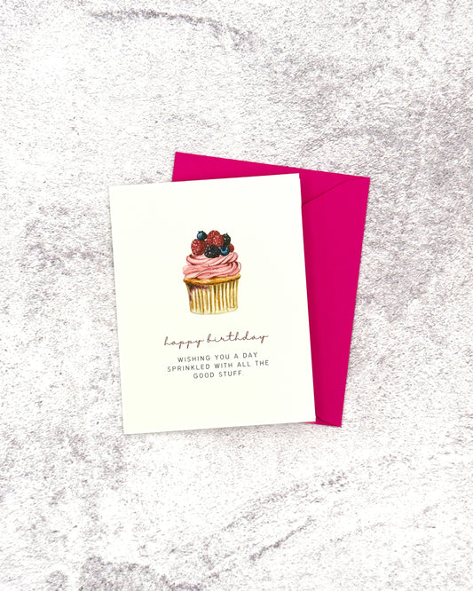 Greeting card with a cupcake illustration and pink envelope on a textured surface