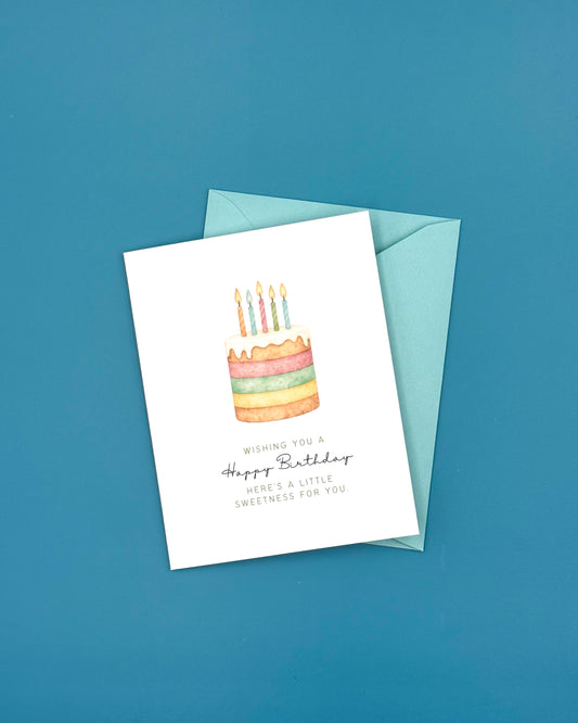 Birthday card with a colorful cake illustration and envelope on a blue background