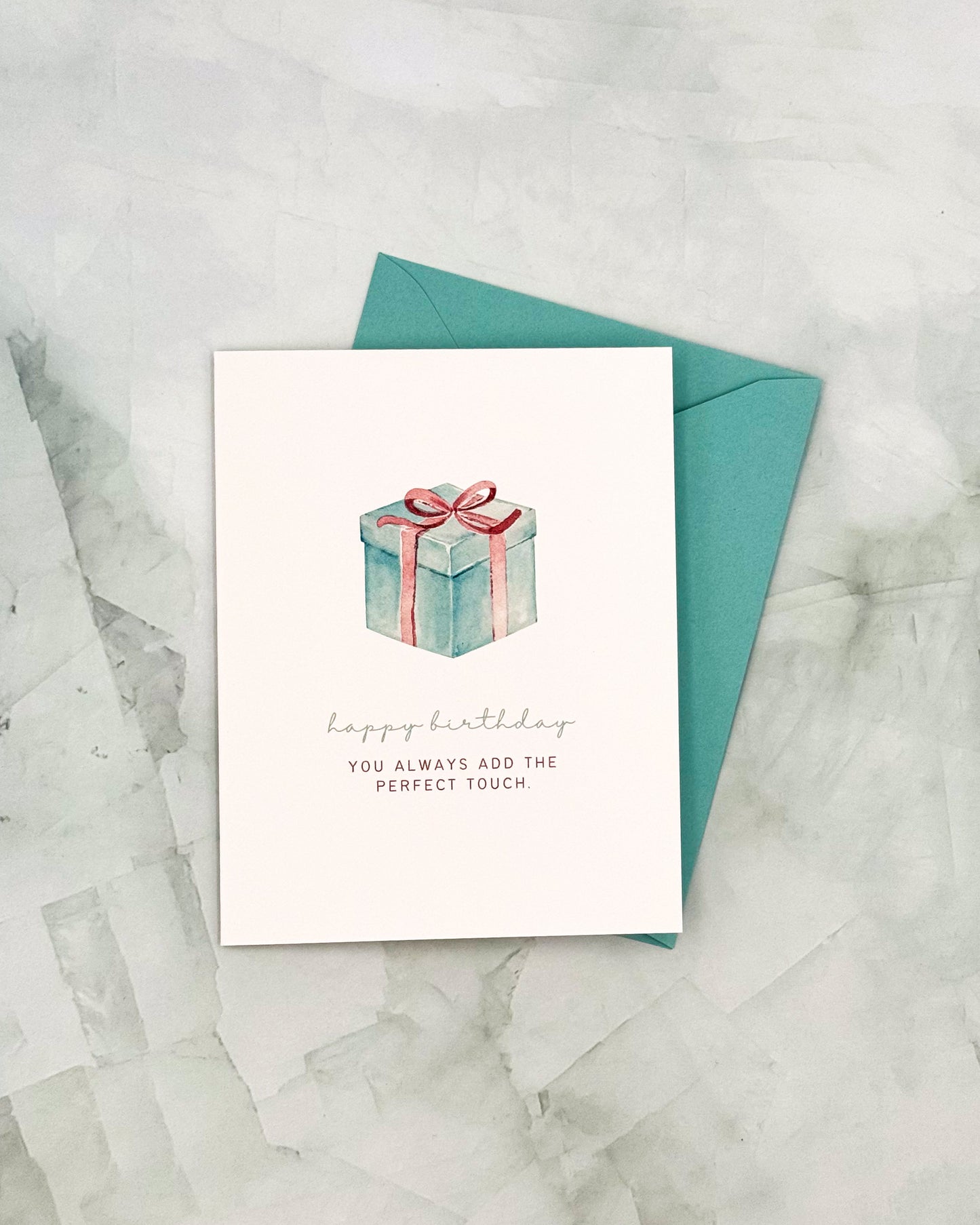 Greeting card with a gift illustration and text on a marble surface