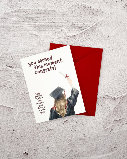 Graduation-themed card with a red envelope on a textured surface