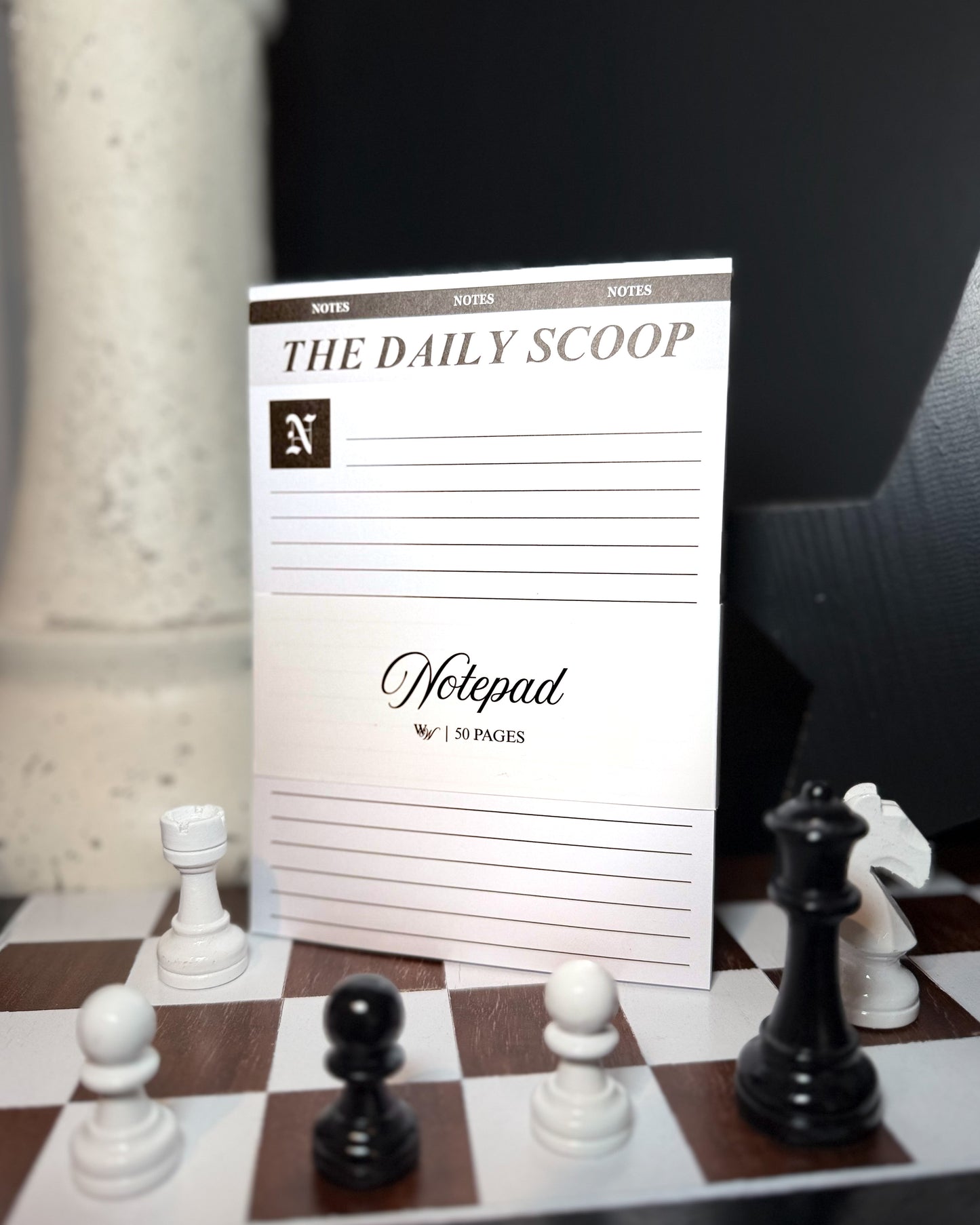 Notepad titled 'The Daily Scoop' on a chessboard with chess pieces.