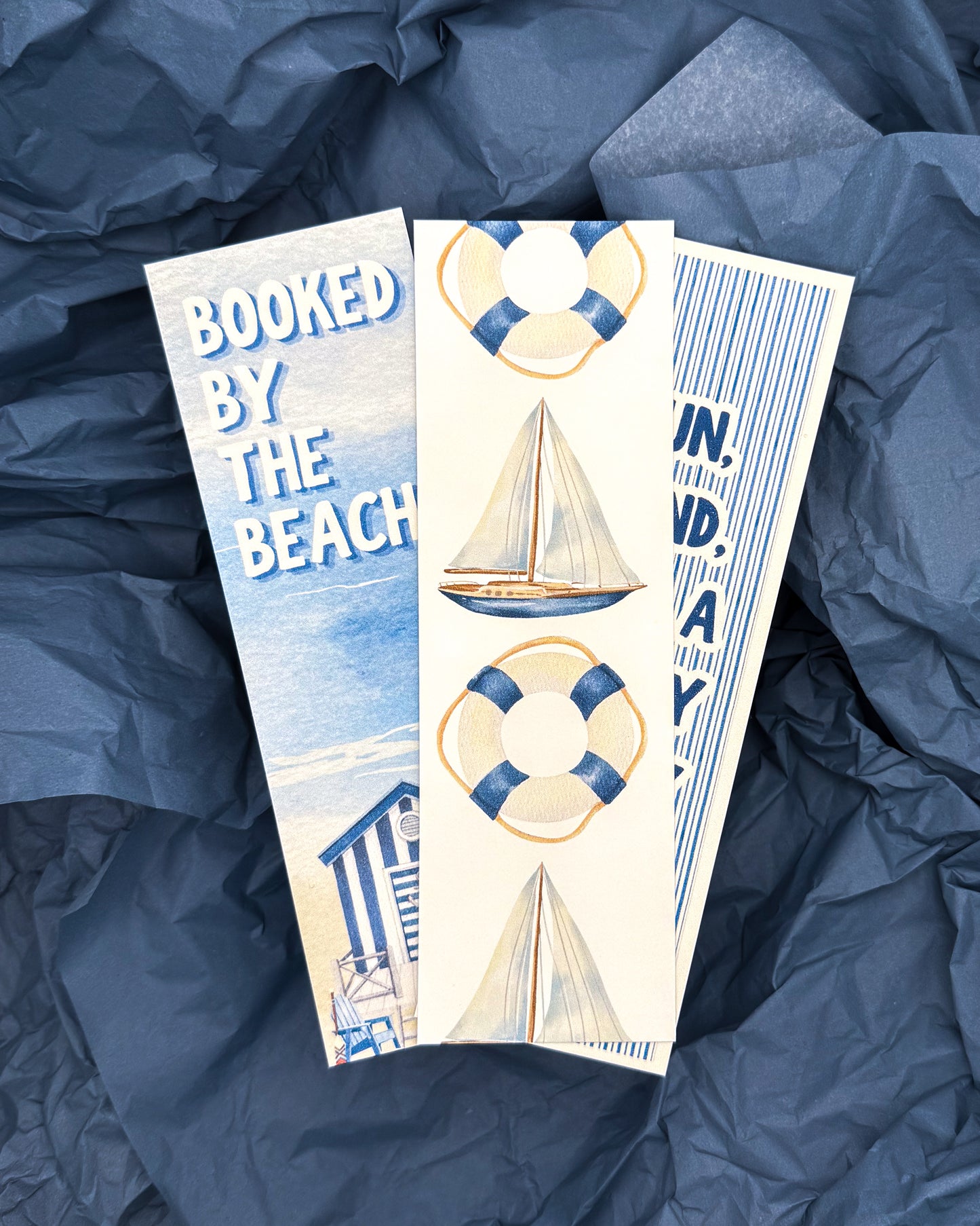 Three beach-themed bookmarks on a blue textured background