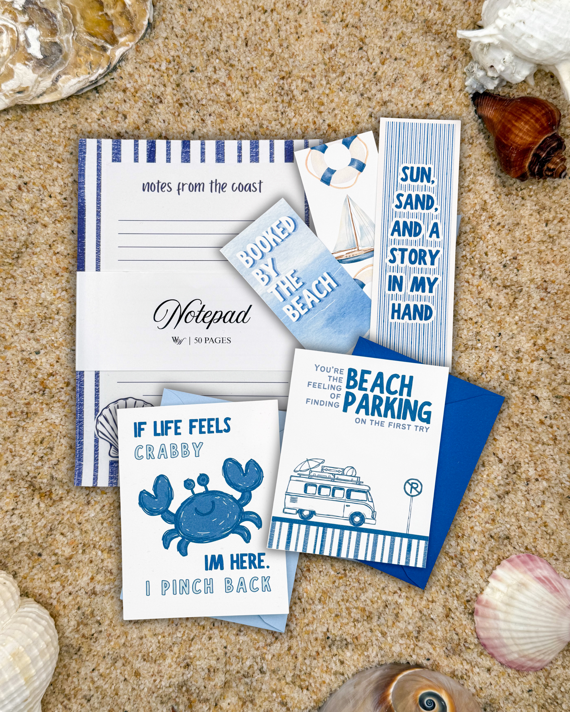Set of beach-themed stationery items on sand with shells around