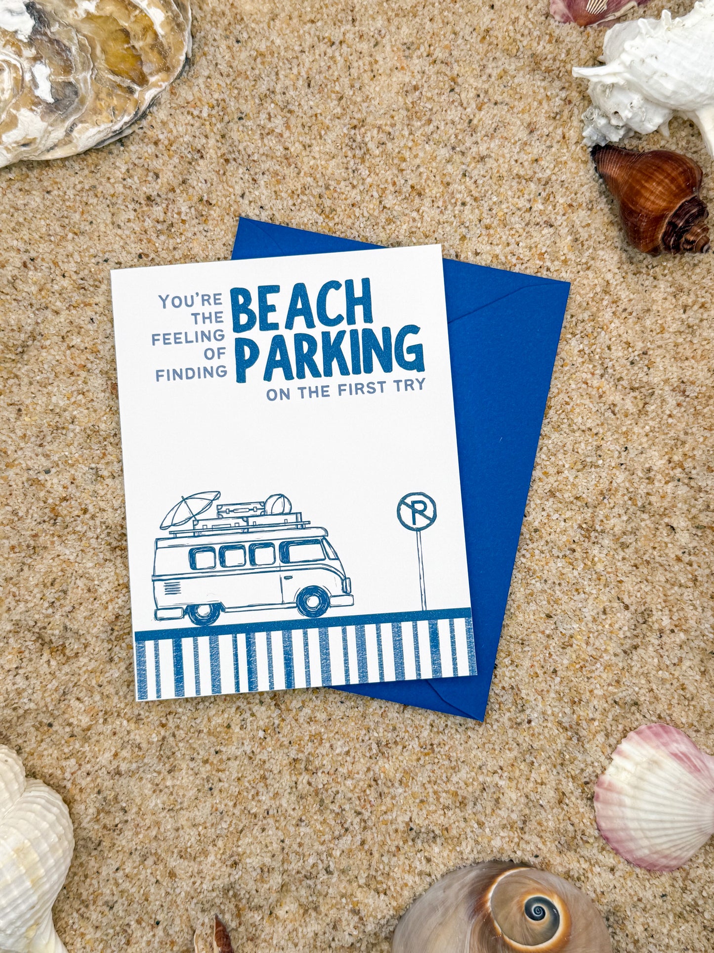 Card with a van illustration and text on sand with shells