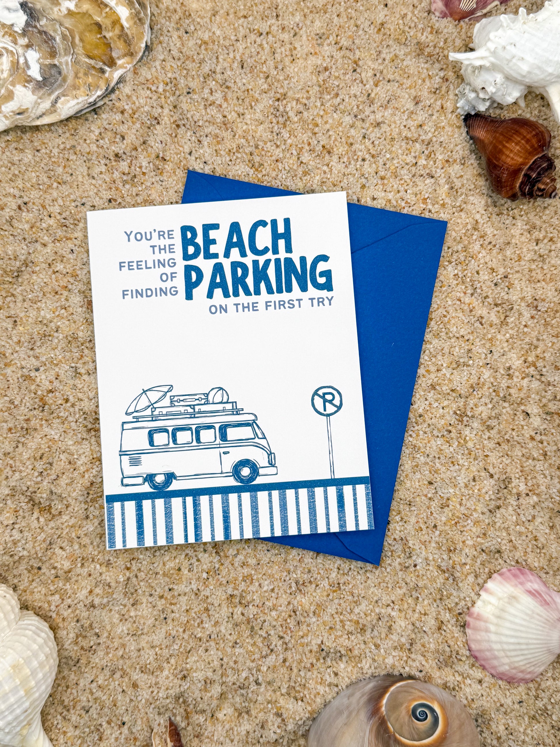 Card with a van illustration and text on sand with shells