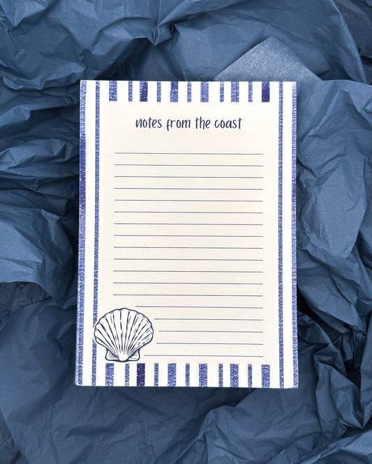 Notepad with 'notes from the coast' text and shell illustration on blue fabric background